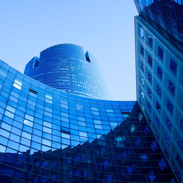 Magnifique batîment d'entreprise bleu avec partie ronde et ciel bleu pur.