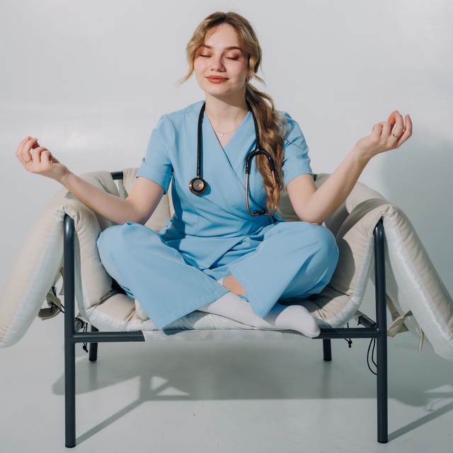 Jeune infirmière assise dans un fauteuil confortable en train de méditer avec son stéthoscope autour du cou.